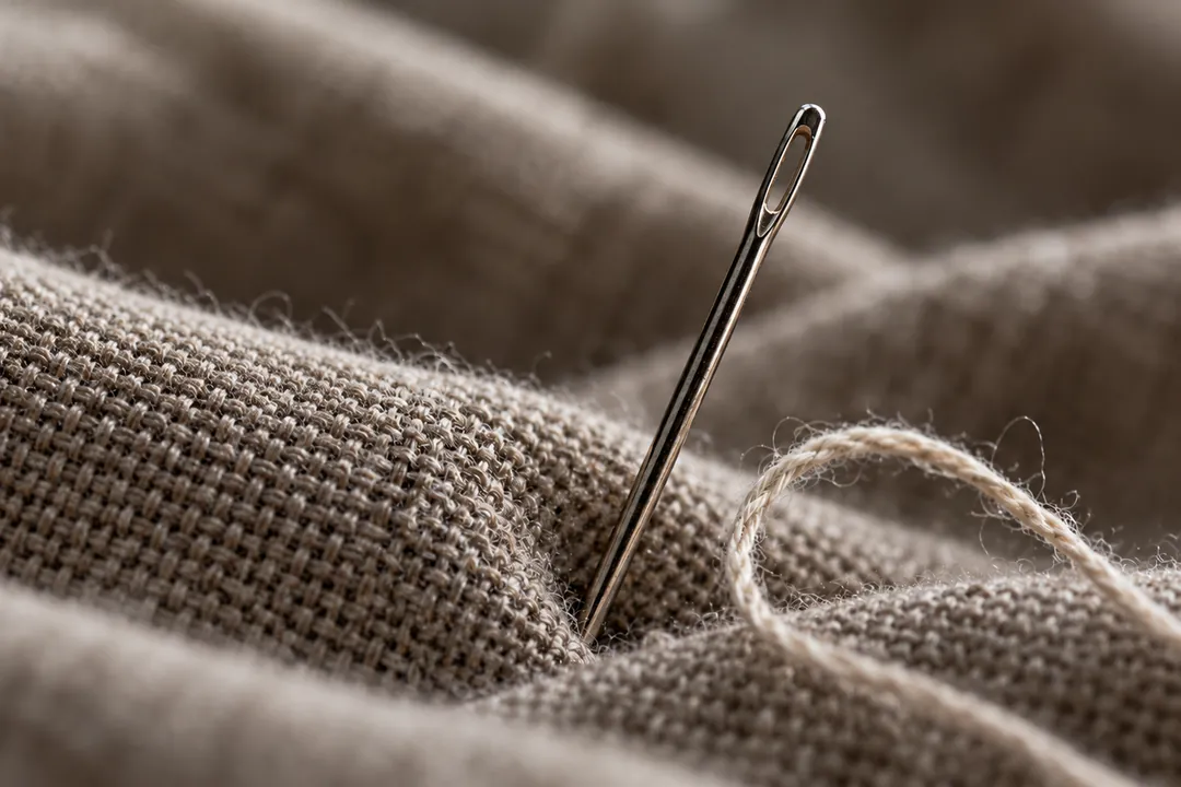 A needle and a loose thread in woven cloth